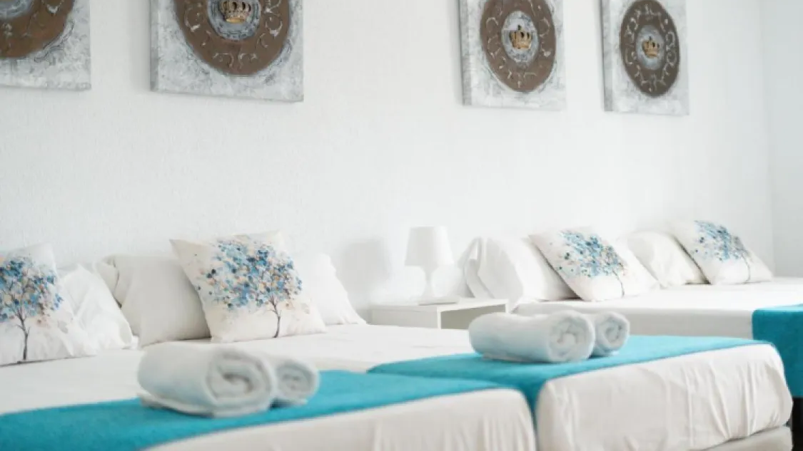 Bedroom with single beds, turquoise runners and folded towels