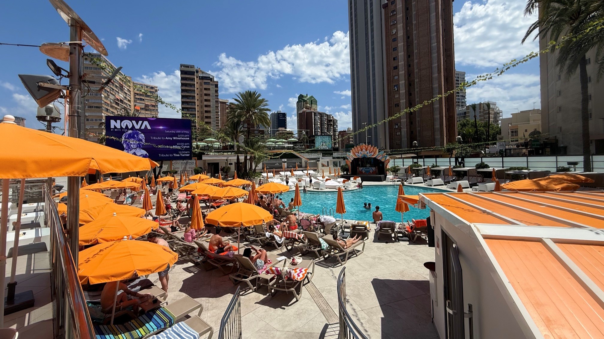 Hotel pool area with orange parasols and city skyscrapers