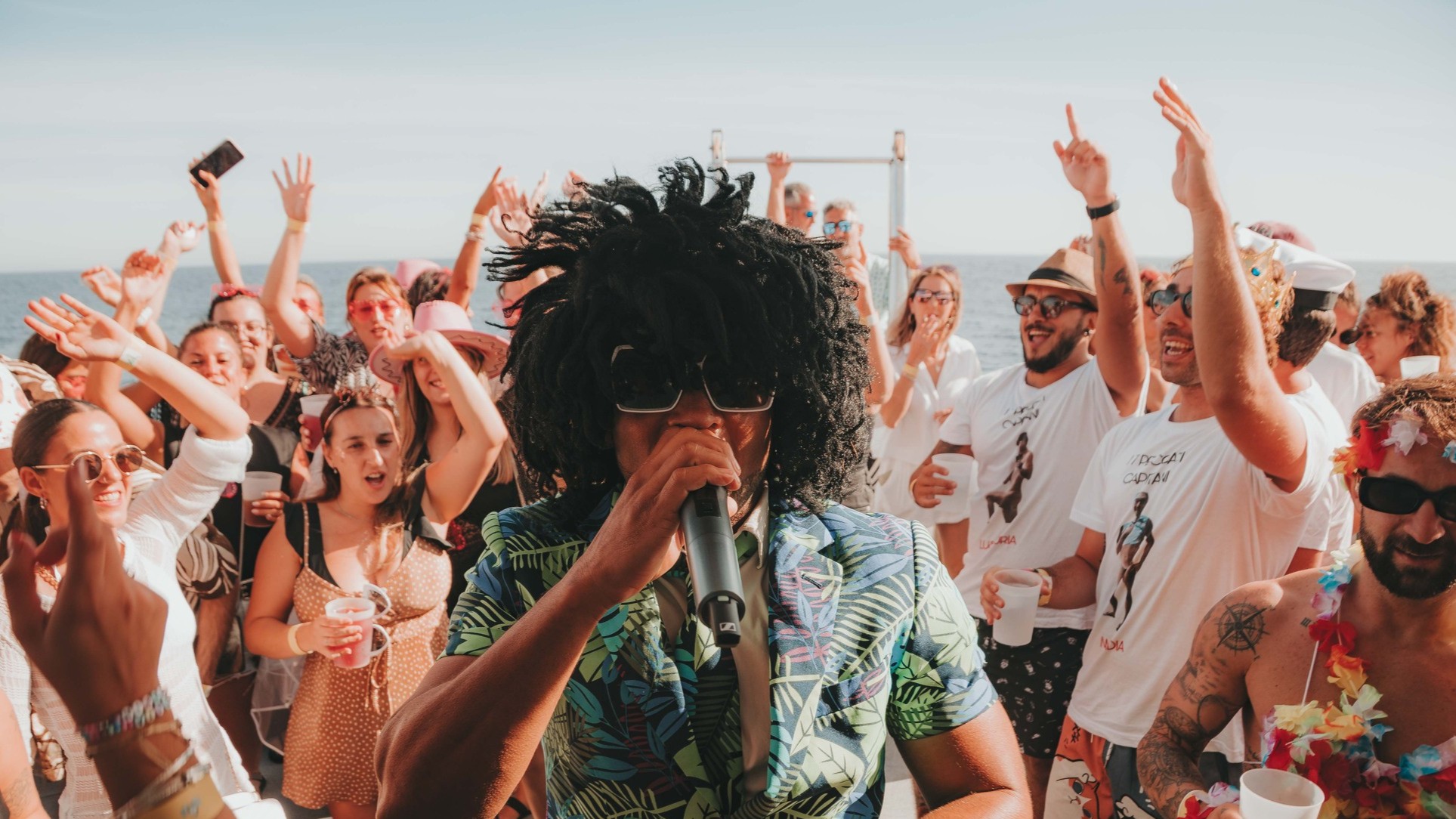 DJ entertaining a crowd dancing on a Benalmadena party boat cruise on the Mediterranean