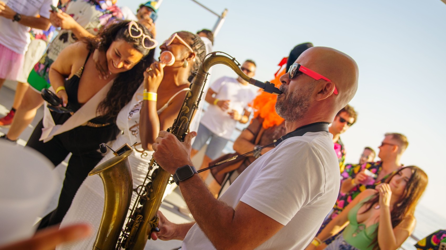Live saxophonist performing on a Benalmadena party boat surrounded by dancing guests